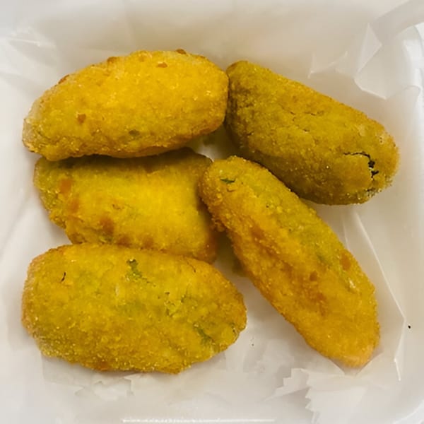 Five golden-fried Indian pakoras, a popular snack, in a white paper-lined container.