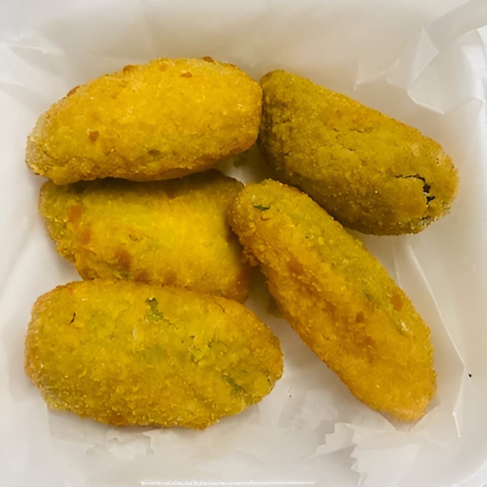 Five golden-fried Indian pakoras, a popular snack, in a white paper-lined container.